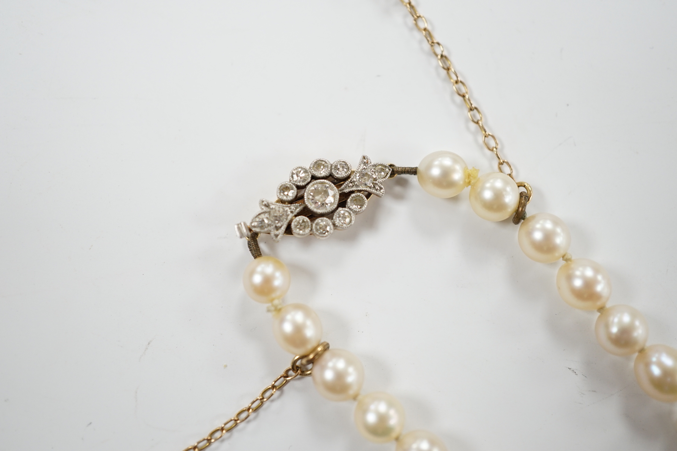 A single strand graduated cultured pearl necklace with millegrain set diamond cluster and yellow metal clasp, 40cm.